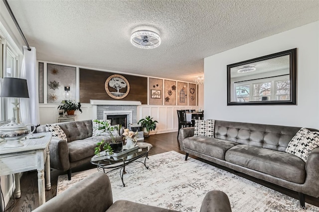 living room featuring a fireplace, wood finished floors, a decorative wall, and a textured ceiling