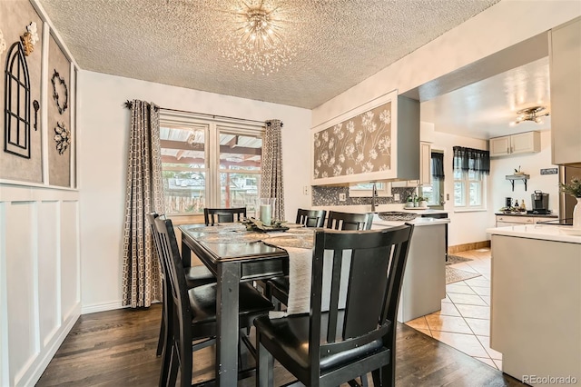 dining space with a textured ceiling, an inviting chandelier, and light wood-type flooring