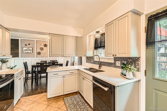 kitchen featuring light countertops, dishwasher, tasteful backsplash, a sink, and stainless steel electric stove