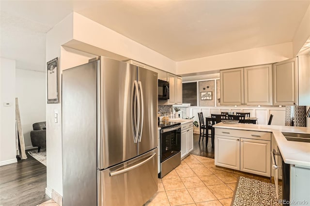 kitchen with light countertops, light tile patterned floors, stainless steel appliances, a sink, and a peninsula
