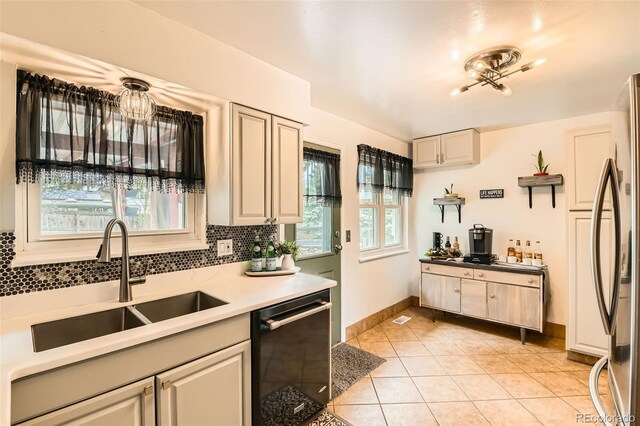 kitchen featuring stainless steel refrigerator, a sink, light tile patterned floors, black dishwasher, and decorative backsplash