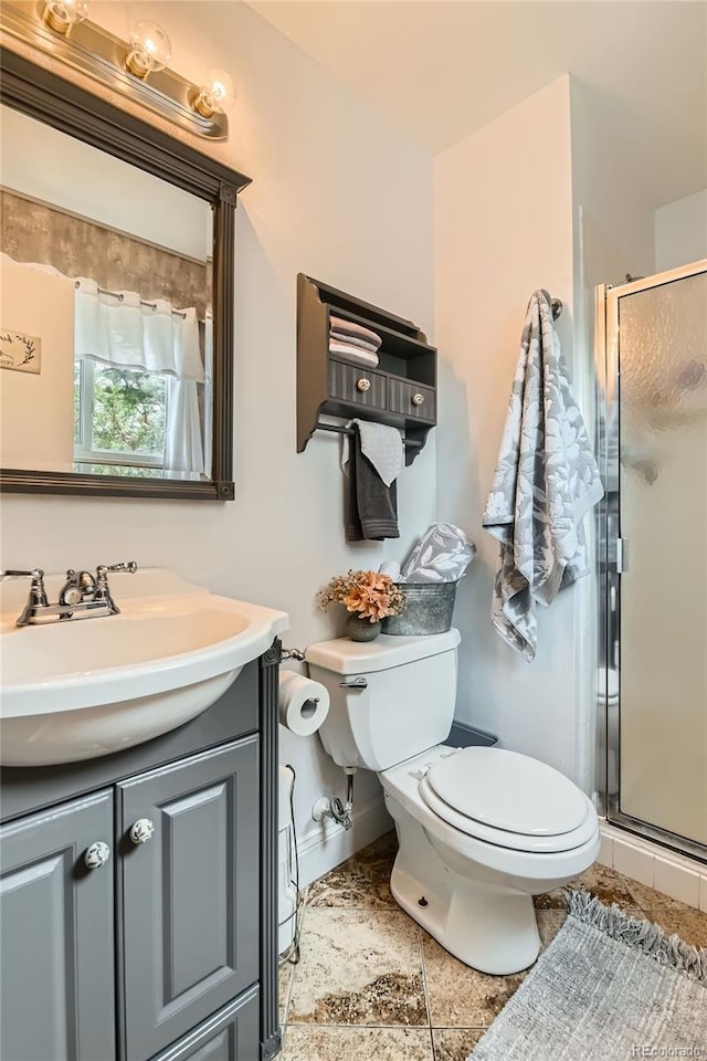full bathroom with toilet, vanity, a stall shower, and baseboards