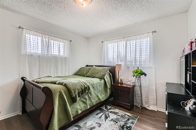 bedroom with a textured ceiling, baseboards, and wood finished floors