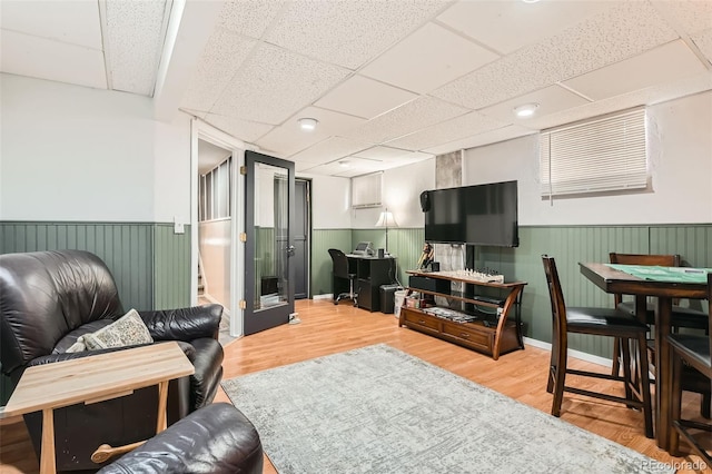living area with wainscoting, wood finished floors, and a drop ceiling