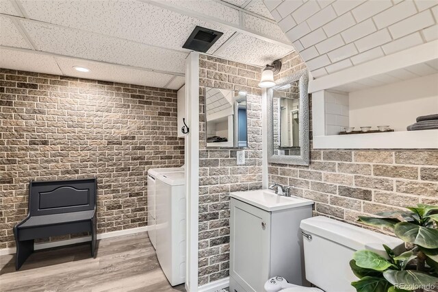 bathroom featuring visible vents, independent washer and dryer, wood finished floors, brick wall, and a paneled ceiling