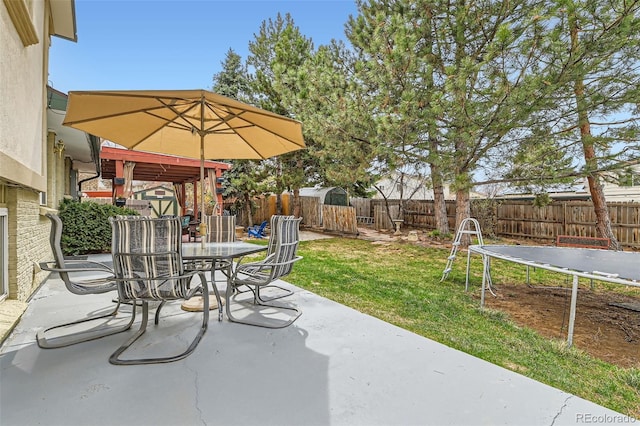 view of patio / terrace featuring a fenced backyard, outdoor dining area, and a trampoline