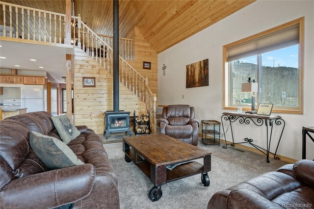 16395 Meadow Dr, Walsenburg, CO 81089 - carpeted living room with high vaulted ceiling, stairs, wooden walls, a wood stove, and wooden ceiling