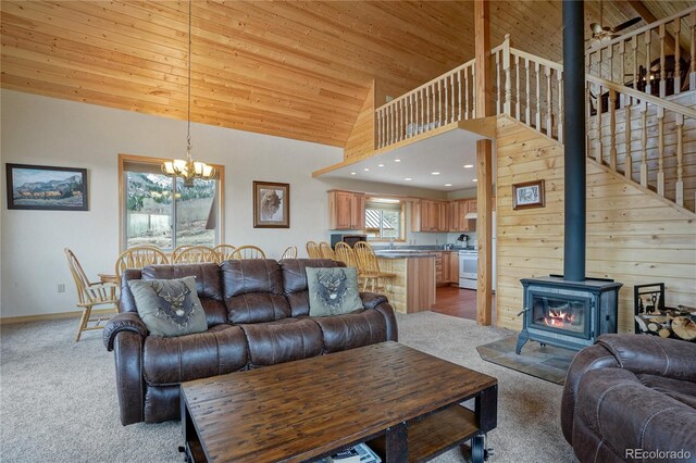 16395 Meadow Dr, Walsenburg, CO 81089 - carpeted living room featuring a wood stove, a wealth of natural light, high vaulted ceiling, and an inviting chandelier