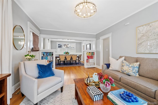 living area featuring crown molding, a notable chandelier, baseboards, and wood finished floors