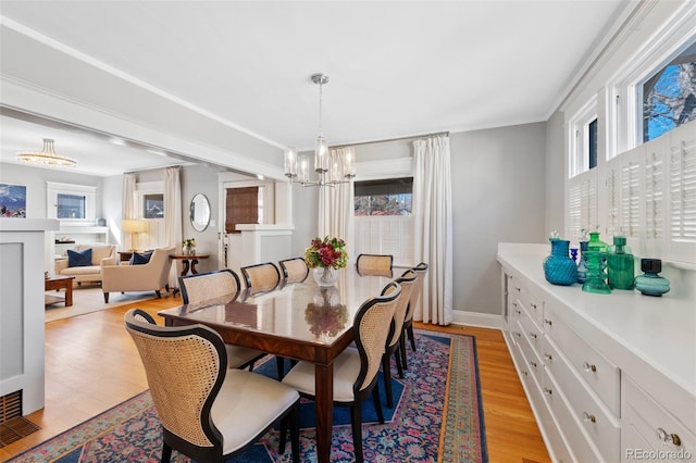 dining area with a chandelier, light wood-style flooring, and baseboards