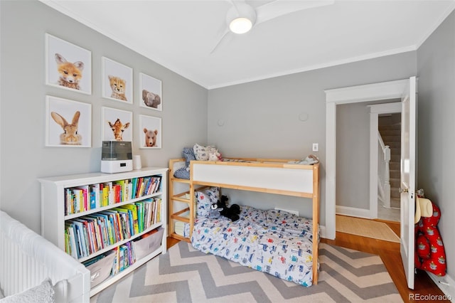 bedroom with crown molding, baseboards, and wood finished floors