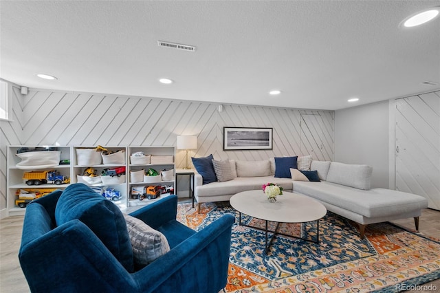 living room featuring recessed lighting, visible vents, a textured ceiling, and wood finished floors