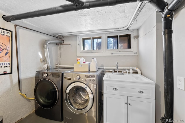 laundry area featuring cabinet space, a textured ceiling, separate washer and dryer, and a sink