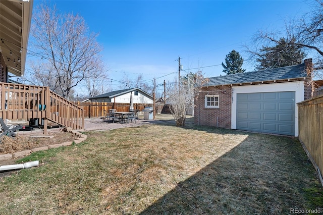 view of yard with an outbuilding, an attached garage, a fenced backyard, driveway, and a patio area