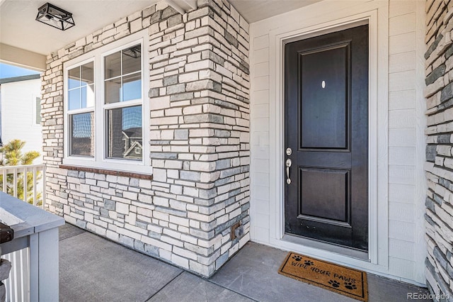 doorway to property featuring a porch and brick siding