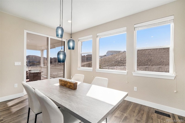 dining space with dark wood-style floors, visible vents, and baseboards