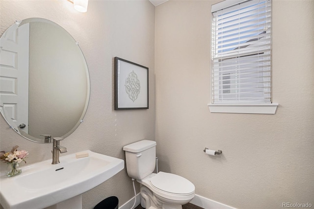 bathroom featuring a sink, baseboards, and toilet