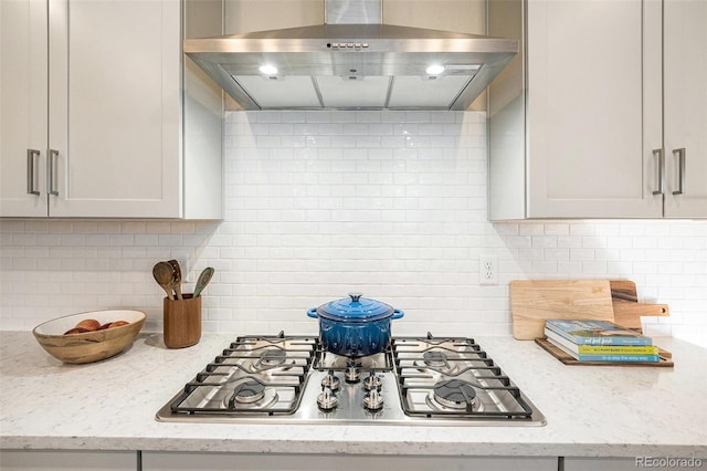 kitchen featuring backsplash, light stone counters, extractor fan, and stainless steel gas cooktop