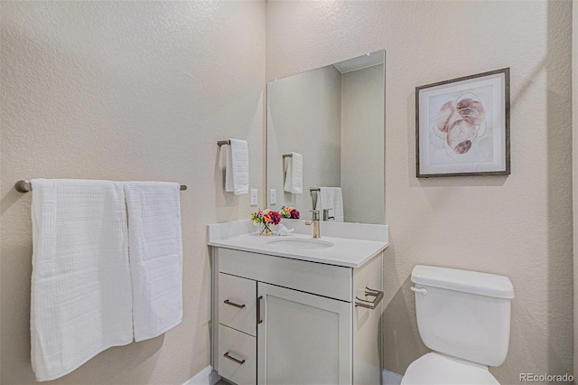 half bathroom featuring vanity and toilet