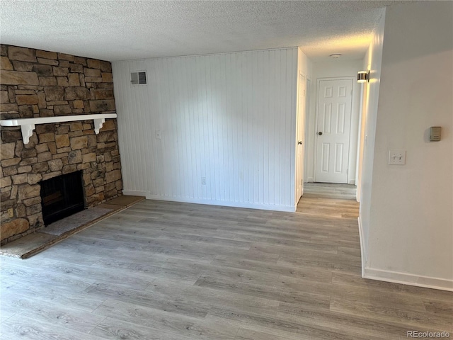 unfurnished living room with light wood-type flooring, a textured ceiling, and a fireplace