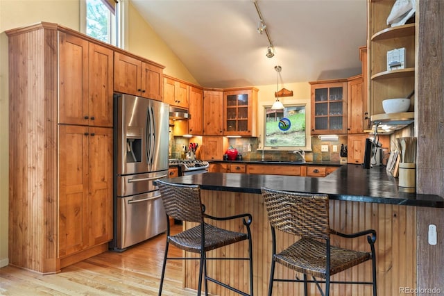 207 Kelly Rd E, Boulder, CO 80302 - kitchen with stainless steel appliances, under cabinet range hood, a peninsula, brown cabinetry, and light wood-type flooring