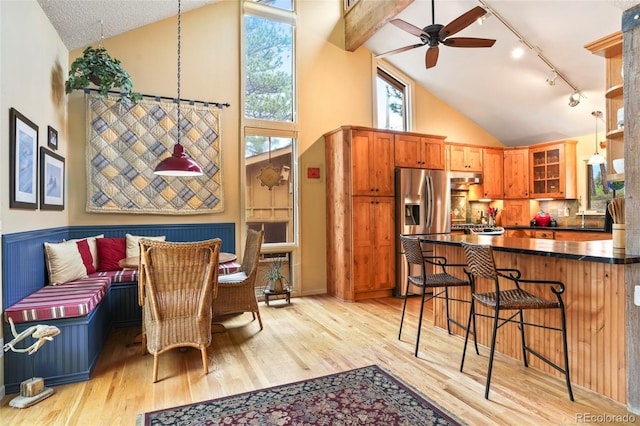 207 Kelly Rd E, Boulder, CO 80302 - kitchen featuring stainless steel fridge with ice dispenser, rail lighting, dark countertops, a breakfast bar area, and light wood-style flooring