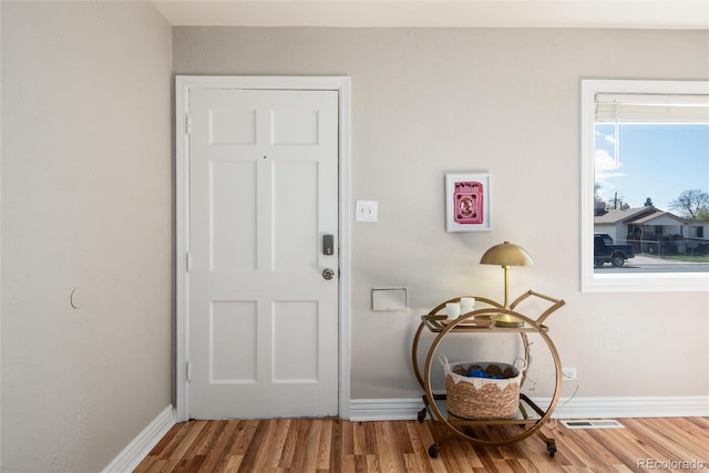 doorway with baseboards, wood finished floors, and visible vents