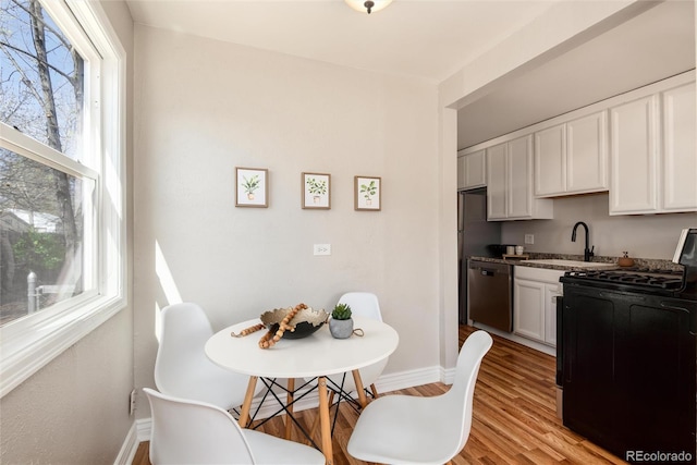 kitchen with a sink, white cabinetry, baseboards, stainless steel dishwasher, and range with gas cooktop