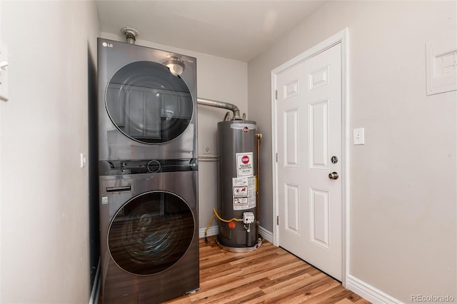 clothes washing area with laundry area, wood finished floors, baseboards, water heater, and stacked washer / drying machine
