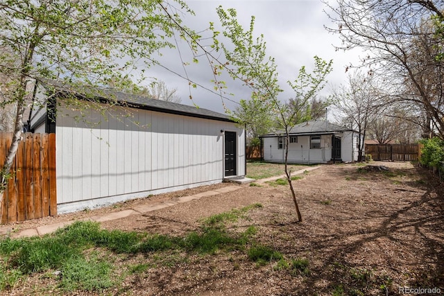 rear view of house featuring fence and an outdoor structure