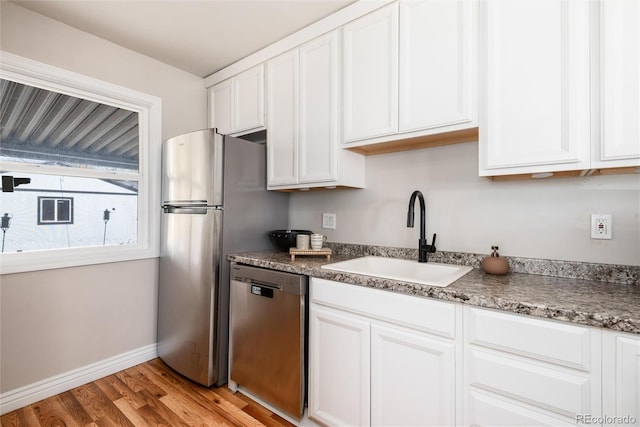 kitchen with light wood-style floors, baseboards, white cabinets, a sink, and dishwasher