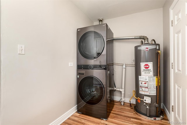 clothes washing area with laundry area, baseboards, light wood-style flooring, water heater, and stacked washer / drying machine