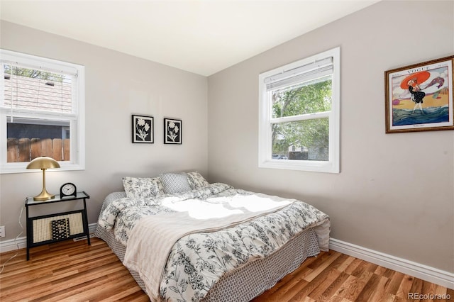 bedroom featuring baseboards, multiple windows, and wood finished floors