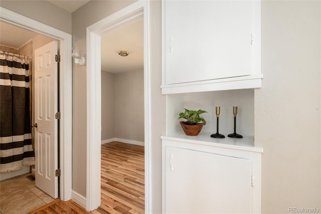 corridor with baseboards and light wood finished floors