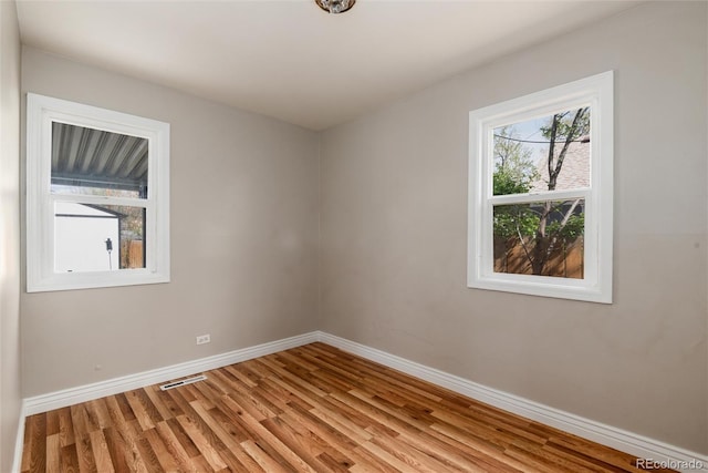 empty room featuring baseboards, visible vents, and light wood-type flooring