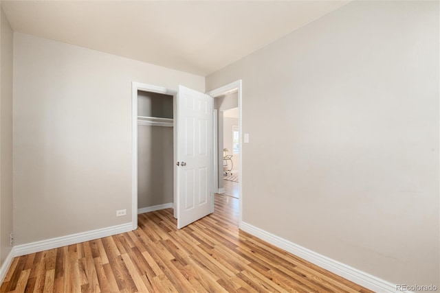 unfurnished bedroom with baseboards, a closet, and light wood-style flooring