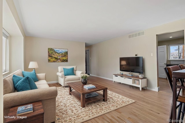 living area with visible vents, baseboards, and wood finished floors