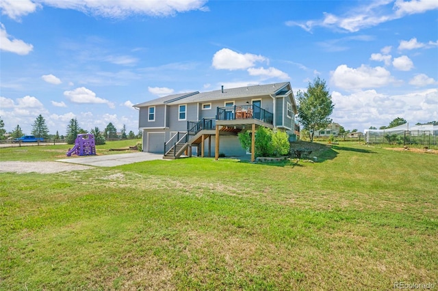 rear view of house featuring a wooden deck, a garage, and a lawn