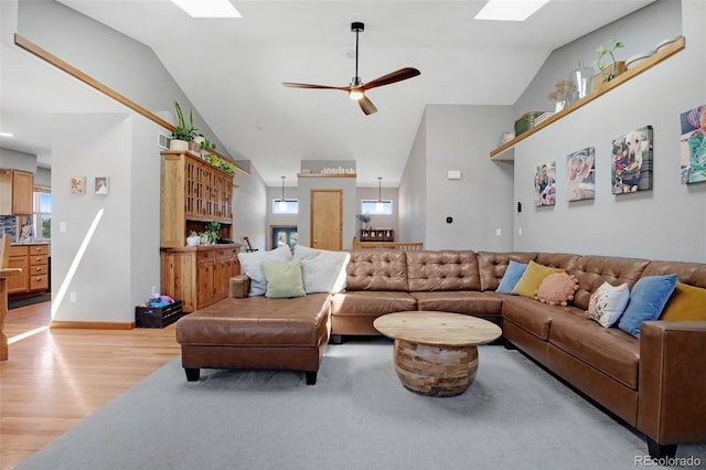 living room featuring light hardwood / wood-style flooring, ceiling fan, and lofted ceiling with skylight