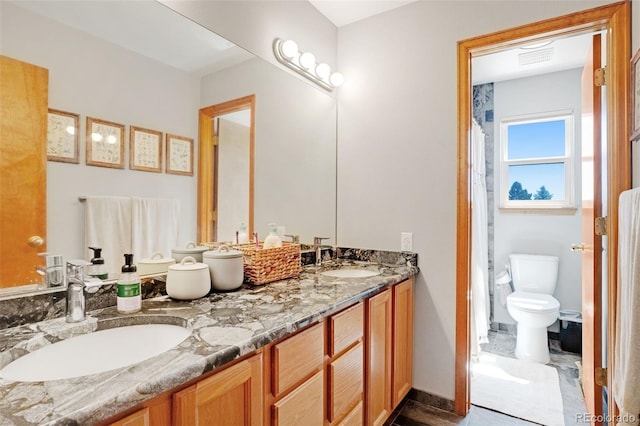 bathroom featuring toilet, double sink vanity, and tile patterned floors