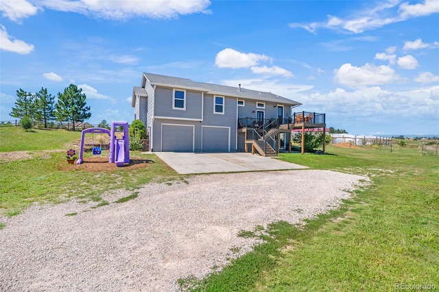 view of front of property with a deck, a front yard, and a garage