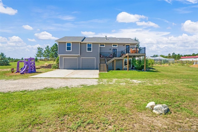 rear view of property with a deck, a garage, and a yard