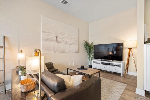 living area featuring wood finished floors, visible vents, and baseboards