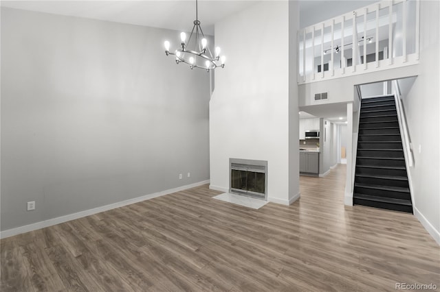 unfurnished living room featuring hardwood / wood-style floors, heating unit, and an inviting chandelier