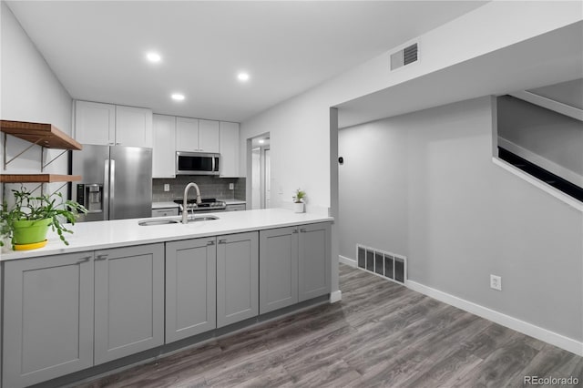 kitchen featuring sink, stainless steel appliances, dark hardwood / wood-style floors, backsplash, and gray cabinets