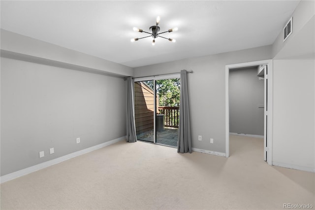 carpeted spare room featuring a notable chandelier