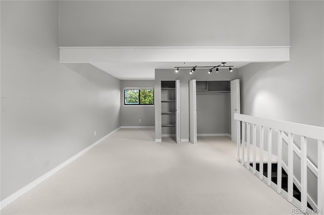 unfurnished bedroom featuring light carpet and rail lighting