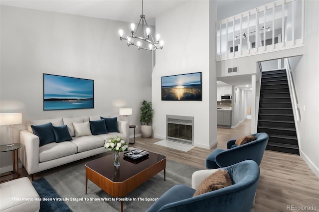 living room with a chandelier, wood-type flooring, and a towering ceiling