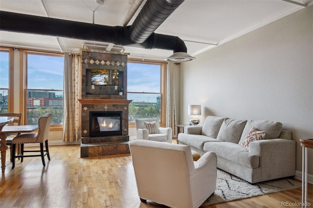 living room with a large fireplace, ornamental molding, and light wood-type flooring