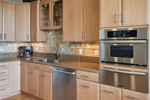 kitchen with sink, light hardwood / wood-style flooring, stone counters, tasteful backsplash, and stainless steel dishwasher